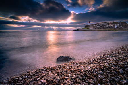 Sunset sky by the lighthouse of urk on the rocky beach at the lake Ijsselmeer by the former island Urk Flevoland Netherlandsの写真素材