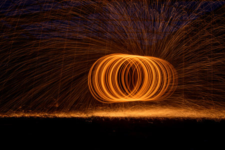 Orange circle moving bright fire light trails on black background.