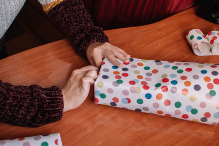 Woman wrapping a Christmas gift. Unrecognizable woman wrapping and decorating a Christmas gift.
