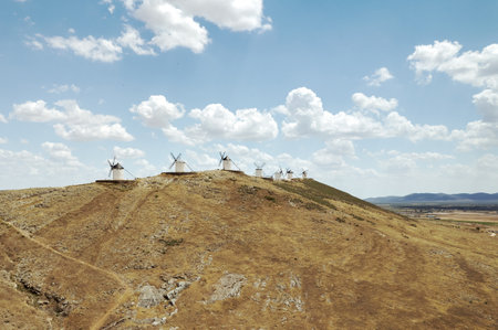 Aerial shot, drone point of view famous windmills in Consuegra town, symbol of Castilla-La Mancha, windmills located on hills against cloudy sky. Heritage, spanish landmarks conceptの写真素材