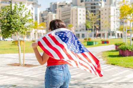 Country, patriotism, independence day and people concept. Young woman with national american flag,...