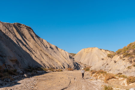 A young hiker with backpack and hat in the desert of Tabernas, AlmerÃ­a province, Andalusia. On a trek in the Rambla del Infiernoの写真素材