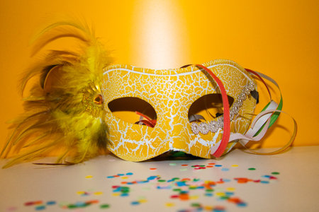 yellow carnival mask with yellow background and colors papersの写真素材