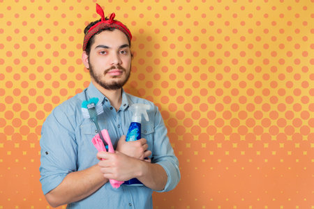 Young man holding cleaning supplies in support of the feminist movement.の写真素材