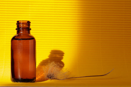 Glass amber skin care bottle on yellow background. Natural lightの写真素材
