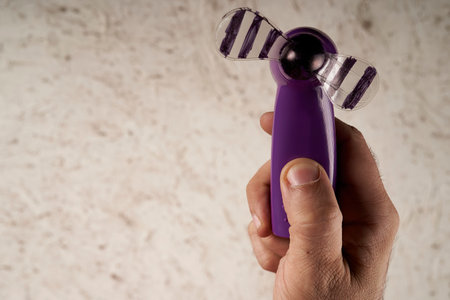 man's hand holding a battery operated hand fanの写真素材