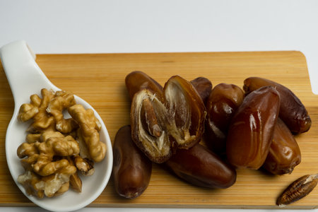 bunch of fresh dates and walnuts on wooden board and ceramic spoonの写真素材