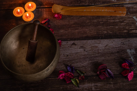handmade tibetan bowl with flower petals and candles in dim lightの写真素材
