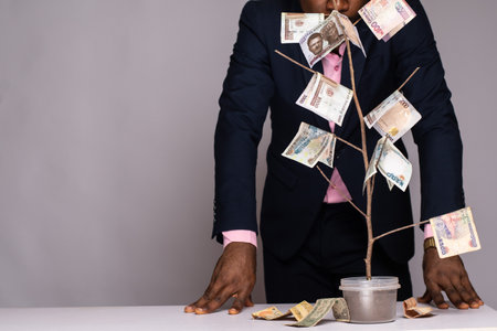 man standing next to a plant with money as leavesの写真素材
