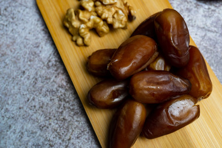 bunch of fresh dates and walnuts on wooden board and ceramic spoonの写真素材