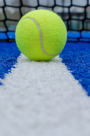 Net of a blue paddle tennis court and a ball on the white line. Racket sports conceptの写真素材