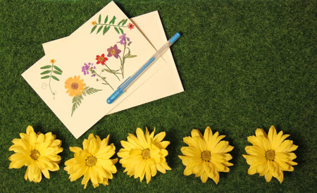 Flowers on Grass With Blank Greeting Card Decorated With Dried Flowersの写真素材