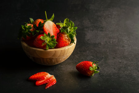 Strawberries in a wooden bowl, dark backgroundの写真素材