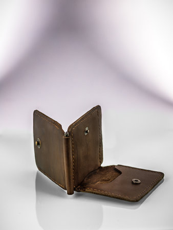 a brown leather wallet lies on a mirror surface on a light gradient background