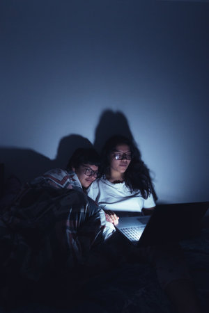 Young women at a sleepover watching movies.の写真素材