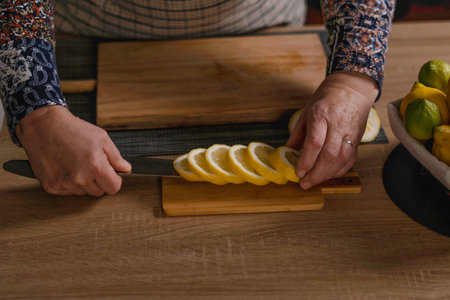 woman's hands cutting lemons and limes on a wooden boardの写真素材