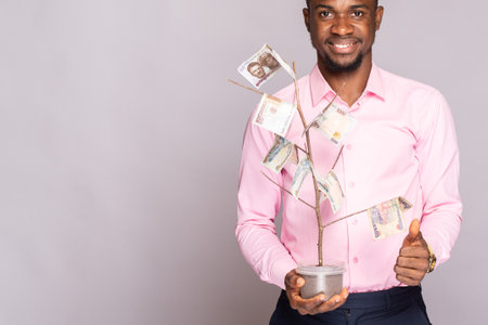 happy young black man holding a money treeの写真素材