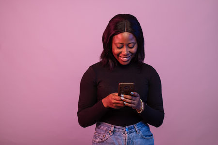 pretty black girl using her phone in colorful lightingの写真素材