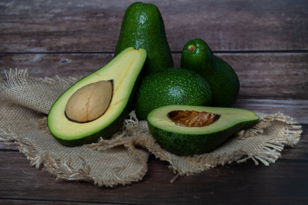 organic avocado from sustainable agriculture from andalucia, spain on a wooden board and on a raffia...