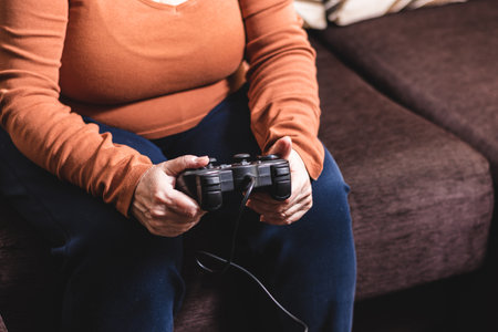 Unrecognizable woman playing video game console. Mature Caucasian woman playing video game console.