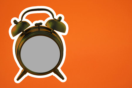 An old green clock with a bell and copy space against orange background. Advertisement idea. Minimal banner ad concept.の写真素材