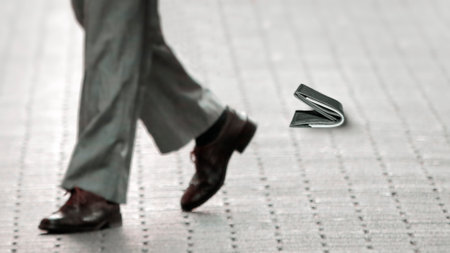 The lost wallet lies on the road near the stair, and in the background are the legs of a businessman