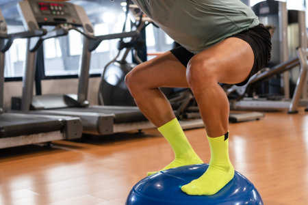 Feet of a Caucasian man in the gym doing balance exercises for the ankle on a rubber sphere, healthy...