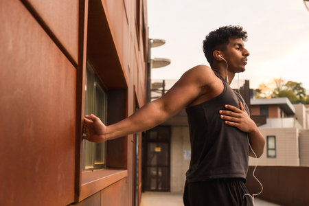 Arab strong young man doing arm stretching exercises before sport in the cityの写真素材