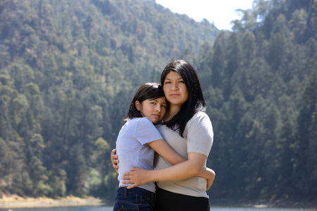 Mexican mother and daughter hugging outdoors, women's dayの写真素材