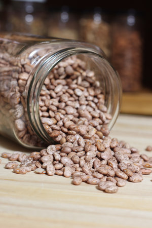 Jar of Pinto Beans Spilled on Kitchen Table With Jars of Beans in Background