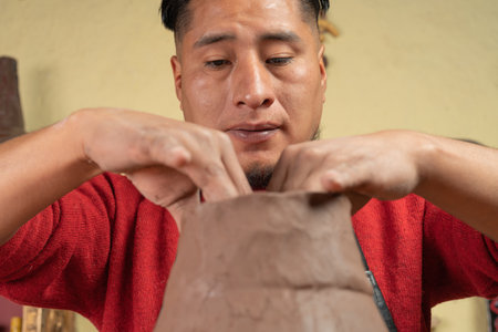 Potter making and molding a ceramic vessel with both hands in his workshop.の写真素材