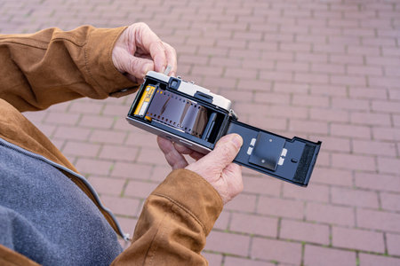 Close-up of an older man placing a film in his old camera.の写真素材