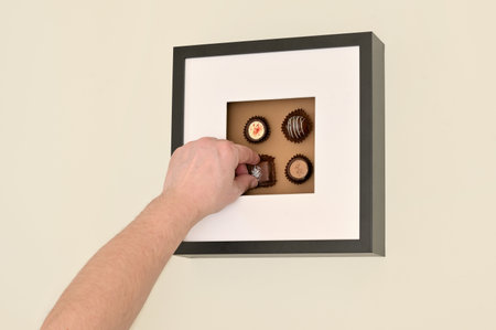 Man's Hand Picking Up Chocolate Pralines in Photo Frame