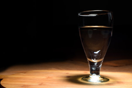 wine glass with wine on wooden table. Top angle lighting shadow comes on the table.