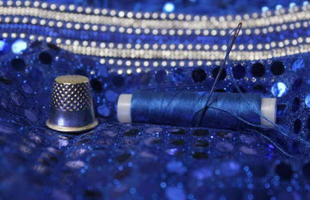 Blue Thread with needle and thimble on blue evening dressの写真素材