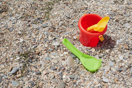 Red bucket, green rake and yellow beach shovel on the beach sand on a sunny summer day, Vera, Spainの写真素材