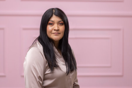 portrait of a mexican empowered woman isolated on pink background