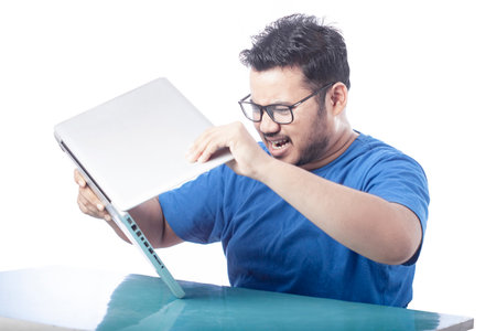 angry student hate technology and breaking laptop with shrieking expression