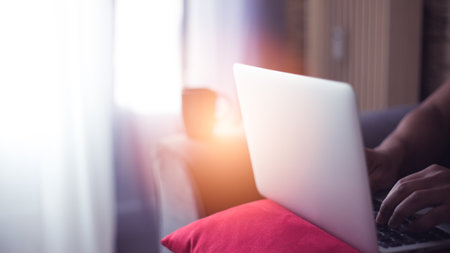 young man at home using his computer and phone having cup of coffeeの写真素材