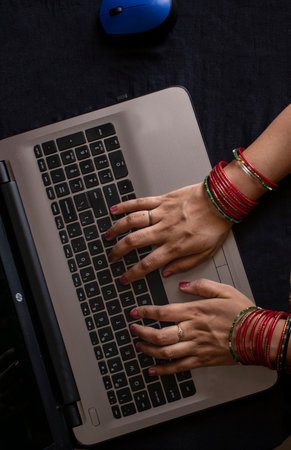 Female wearing bangles and working on laptop.