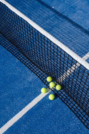 several paddle tennis balls by the net on a blue paddle tennis courtの写真素材