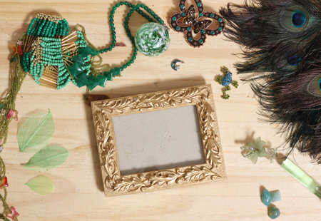 Green Jewelry and Peacock Feathers With Gold Picture Frame on Wood Back
