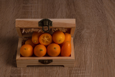 close-up of small Chinese oranges or Kumquat (Citrus sinensis) packed in a wooden box with raffia clothの写真素材
