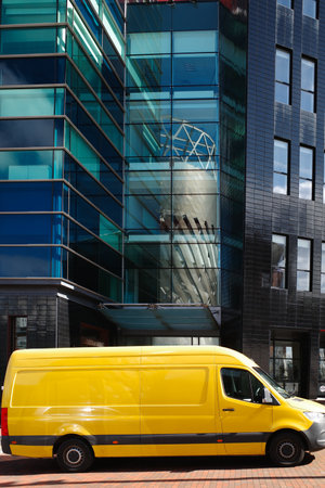 yellow parcel delivery van outside modern glass fronted office building