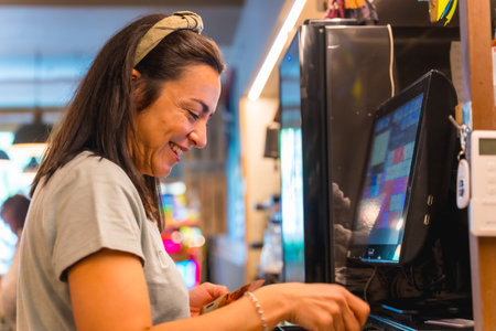 Brunette caucasian waitress smiling doing the check on the computer in the coffee shop