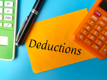 Pen,calculator and colored notepaper with text Deductions on a blue background.の写真素材