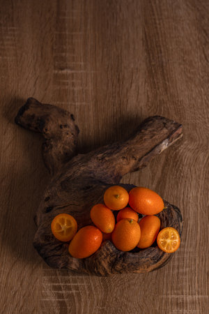 close-up of small Chinese oranges or Kumquat (Citrus sinensis) on a root of a tree on a wooden tableの写真素材