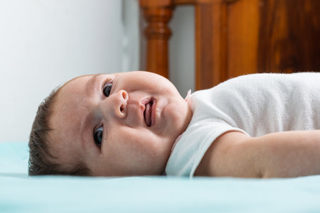 beautiful baby latina with an angry expression on her face as she looks to her right, lying on a bed...