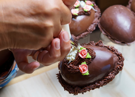hand decorating a chocolate easter egg with a pastry bagの写真素材