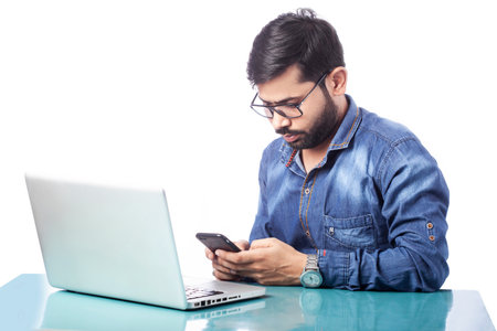 young business man typing on cell phone while working on laptop
